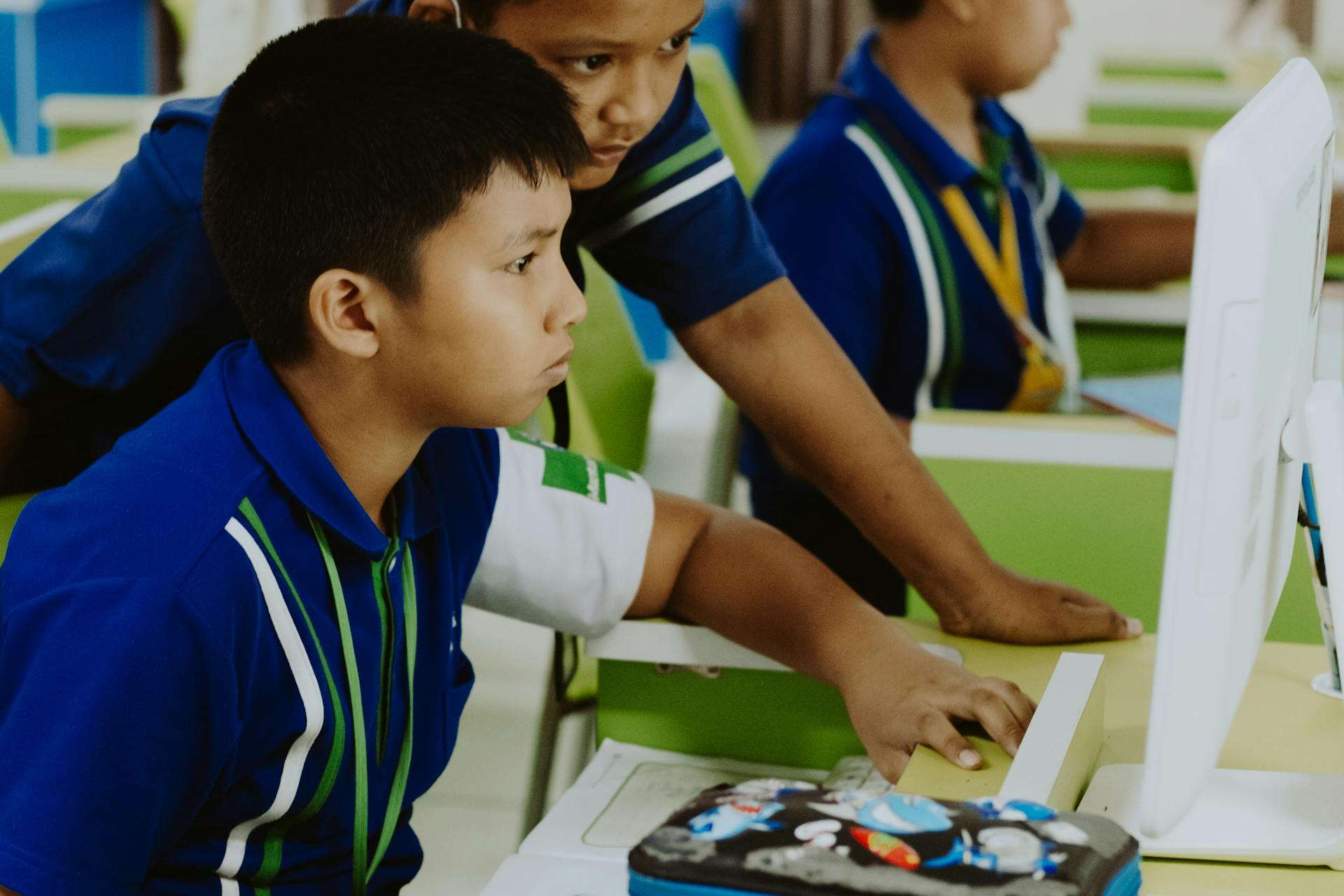 Niños usando ordenadores en un aula luminosa con criterio pedagógico
