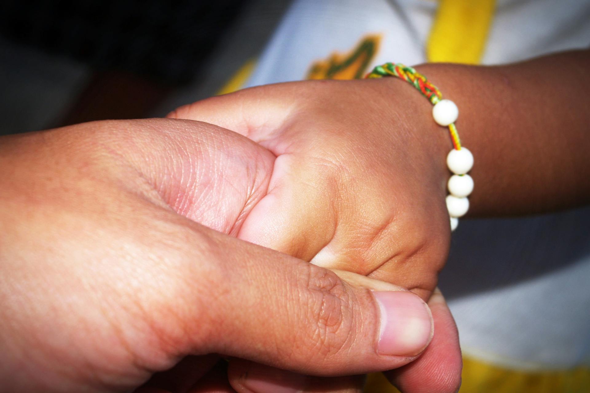 Adulto sosteniendo la mano de un niño, símbolo de protección y confianza
